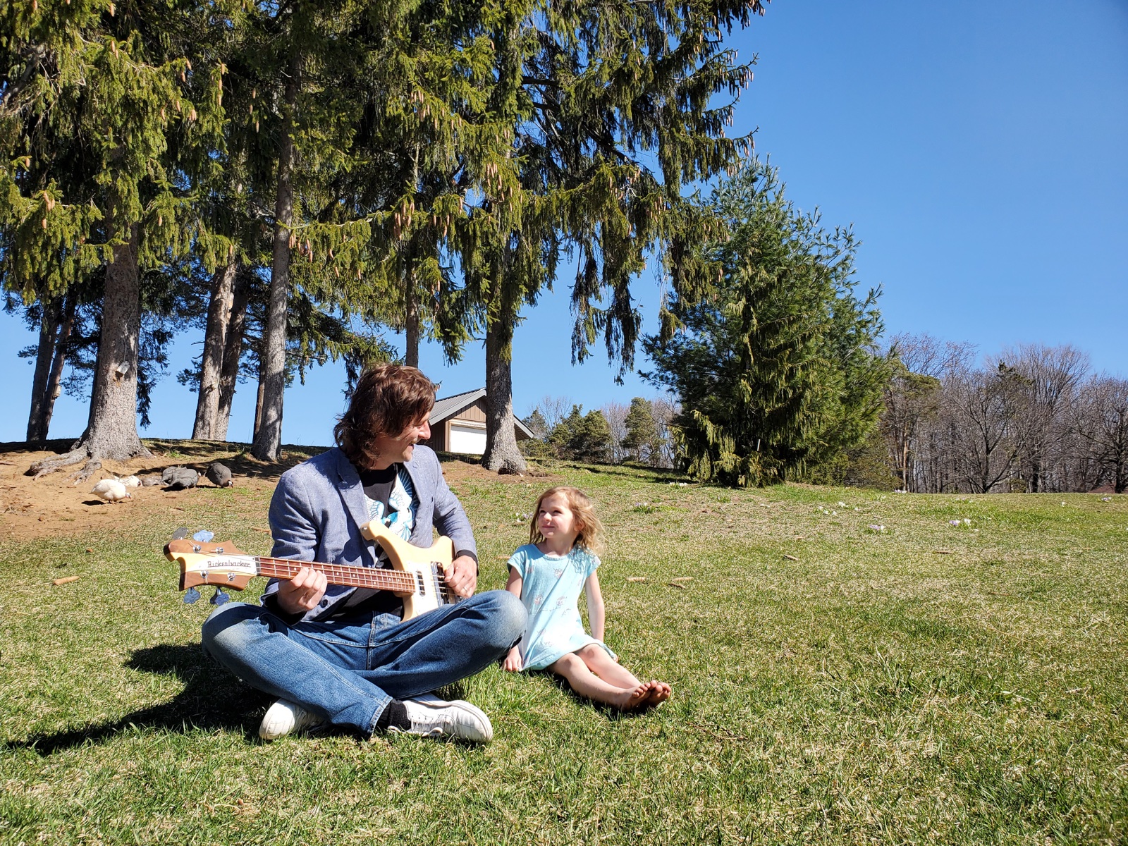 Yuri playing a Rickenbacker bass outdoors with his daughter